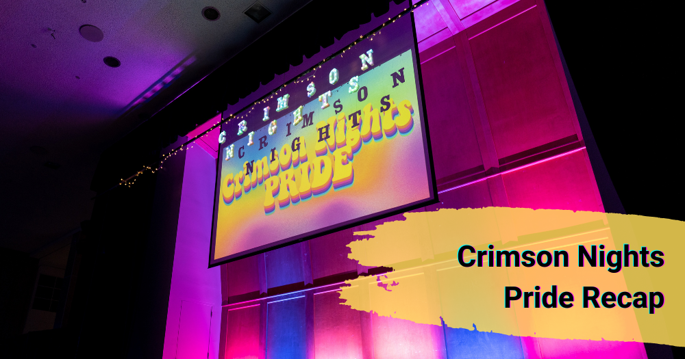 "Crimson Nights Pride Recap" Crimson nights sign projected onto white screen in dark ballroom.