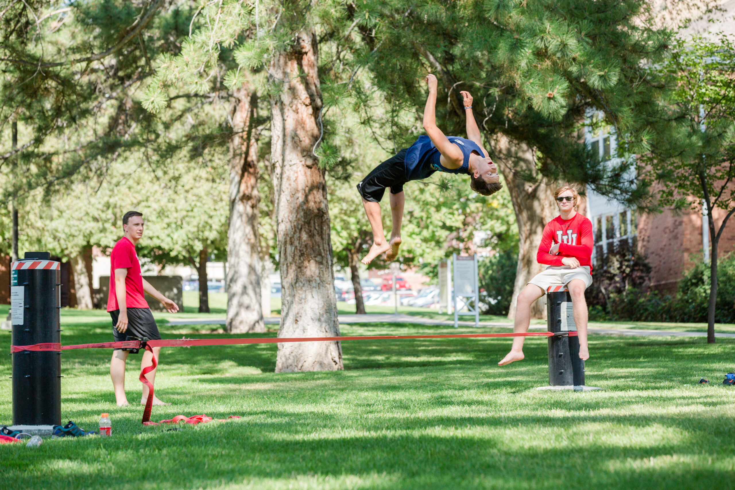 Students standing around and utilizing a slack line.